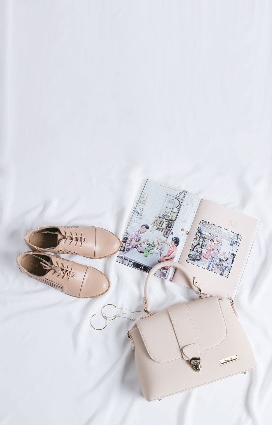 Cartera crema, zapatos con cordones y una revista sobre lino blanco