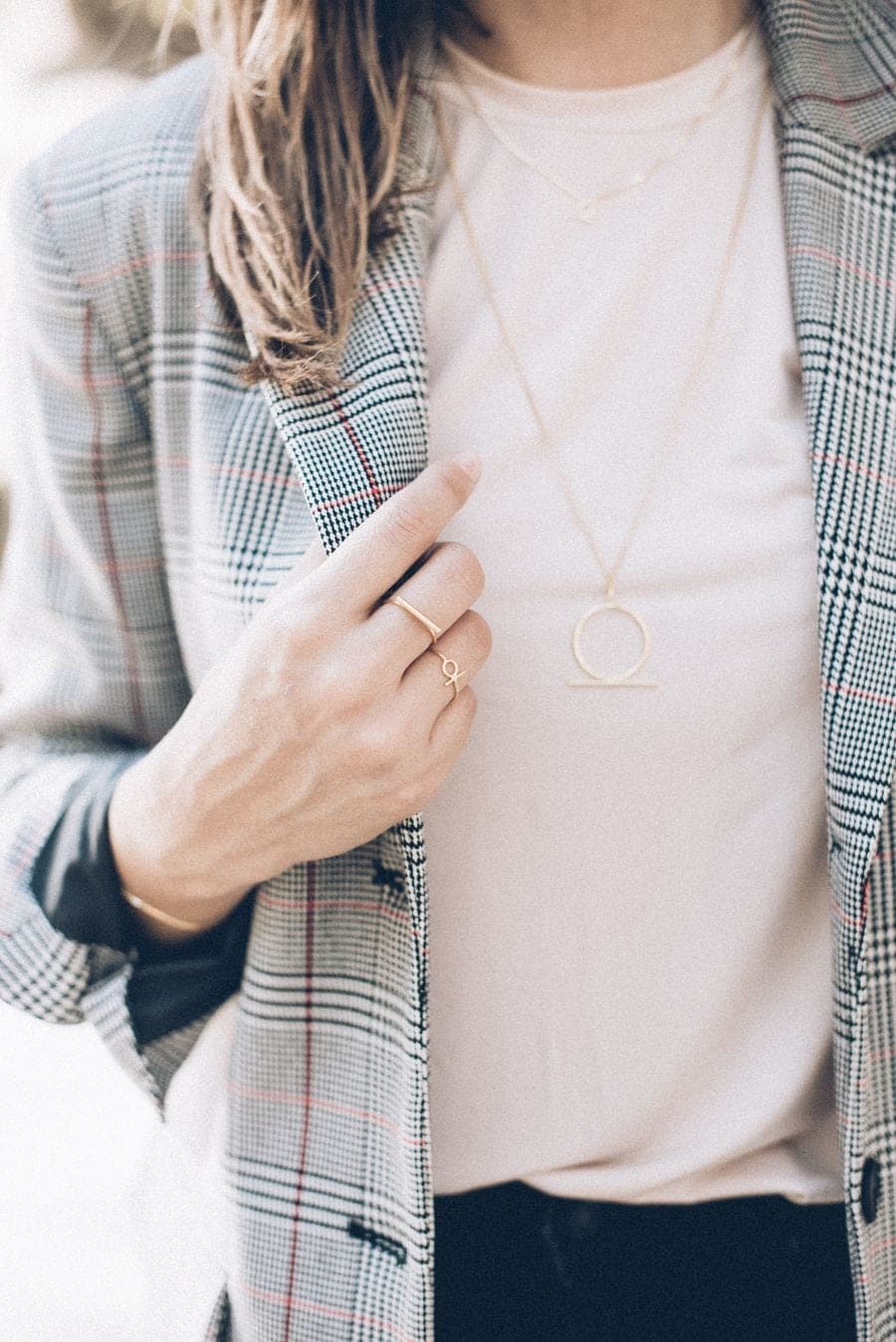 Collar fino y anillos dorados con un blazer a cuadros